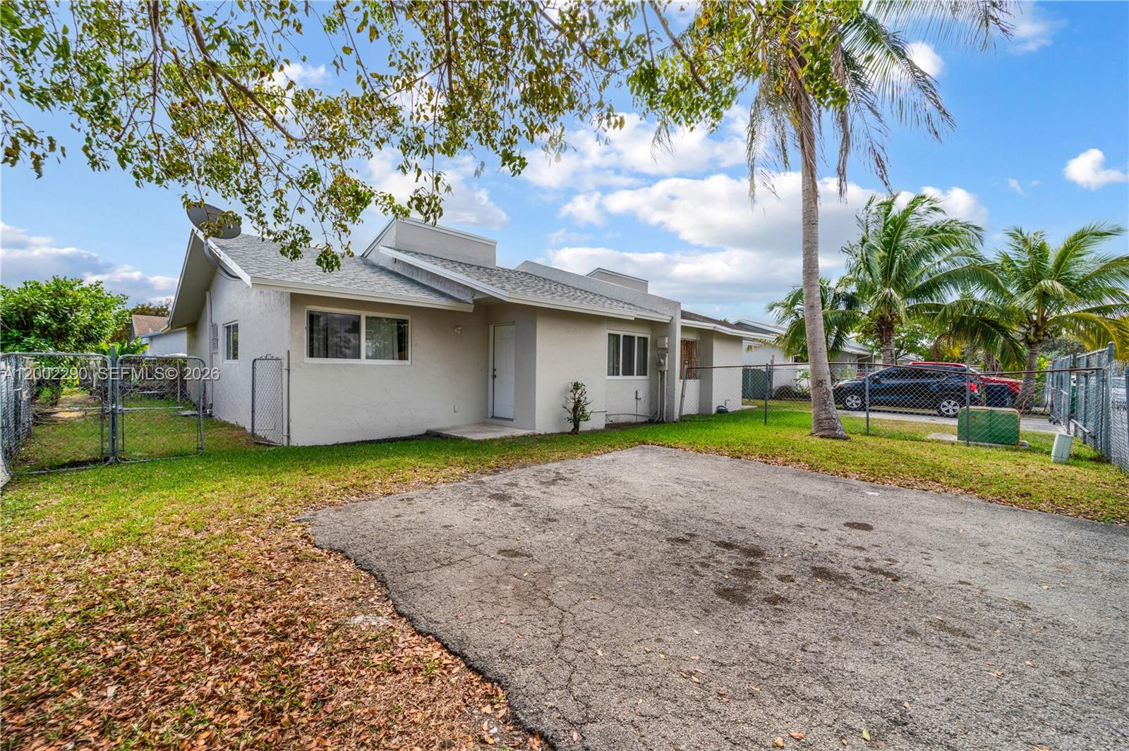 A single-story house with a paved driveway, chain-link fencing, and palm trees — 11310 SW 189th St # 11310, Miami FL 33157, MIAMI, FL