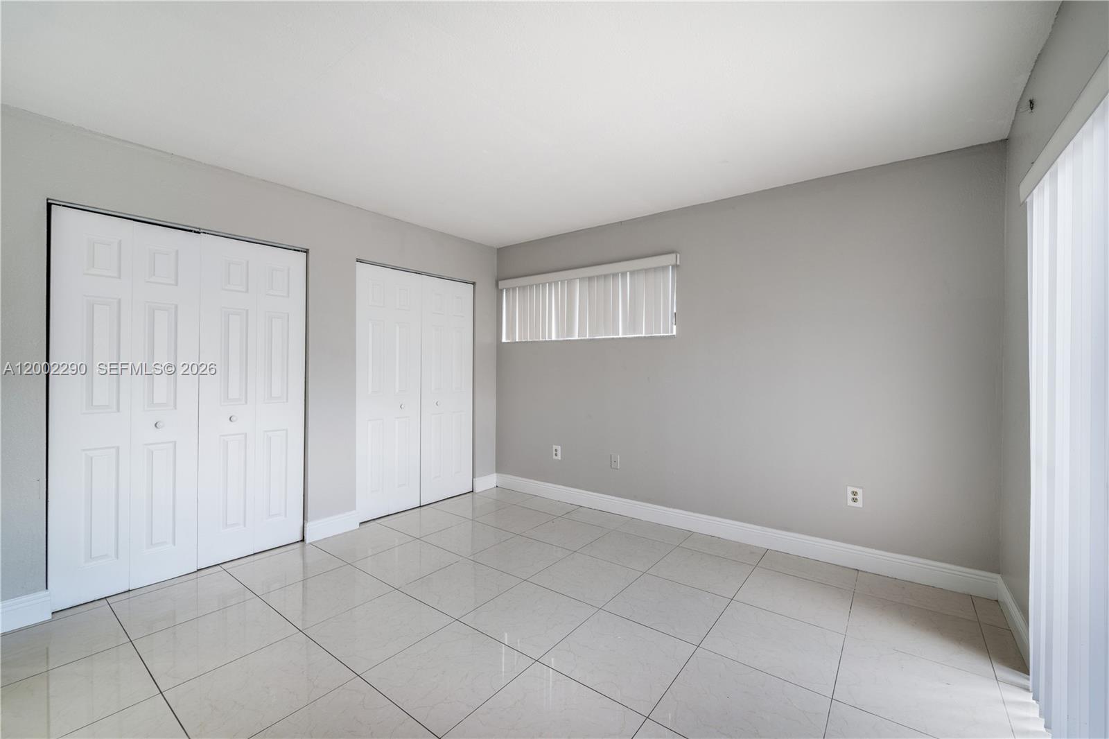 An empty room features light gray walls, white tile flooring, and two sets of closet doors — 11310 SW 189th St # 11310, Miami FL 33157, MIAMI, FL