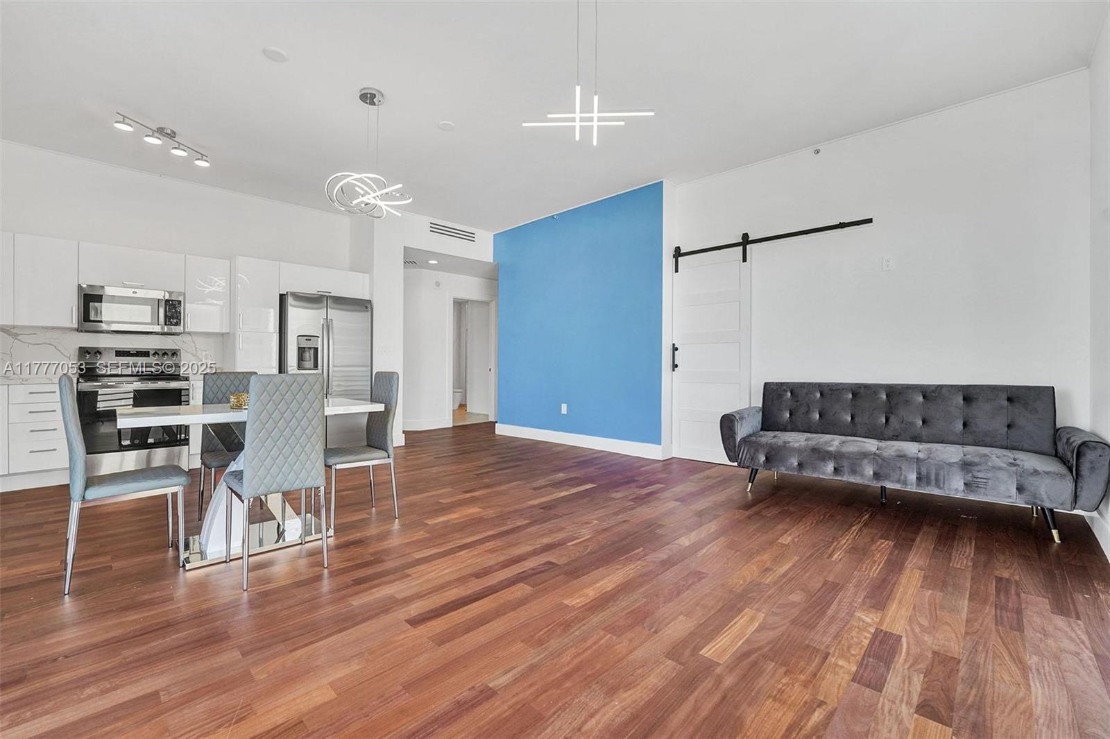 A modern living and dining area features hardwood floors, a blue accent wall, and white cabinetry — 234 NE 3rd St # 2202, Miami FL 33132, MIAMI, FL