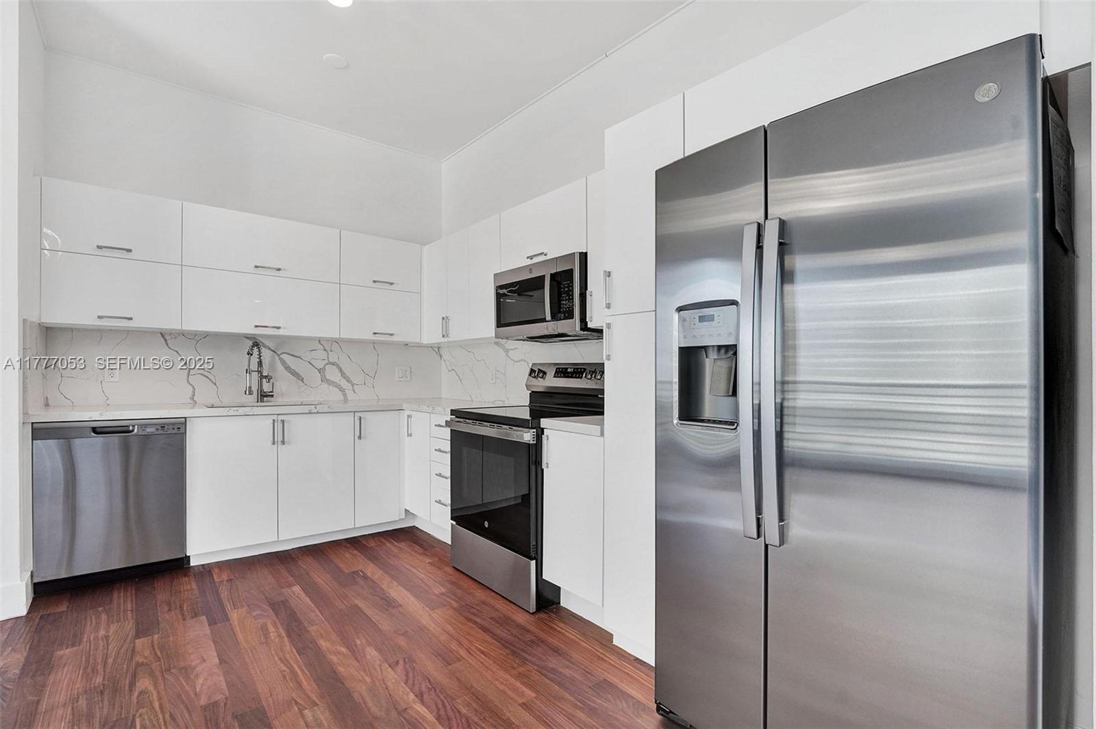 A modern kitchen features white cabinets, stainless steel appliances, and a marble-patterned backsplash — 234 NE 3rd St # 2202, Miami FL 33132, MIAMI, FL