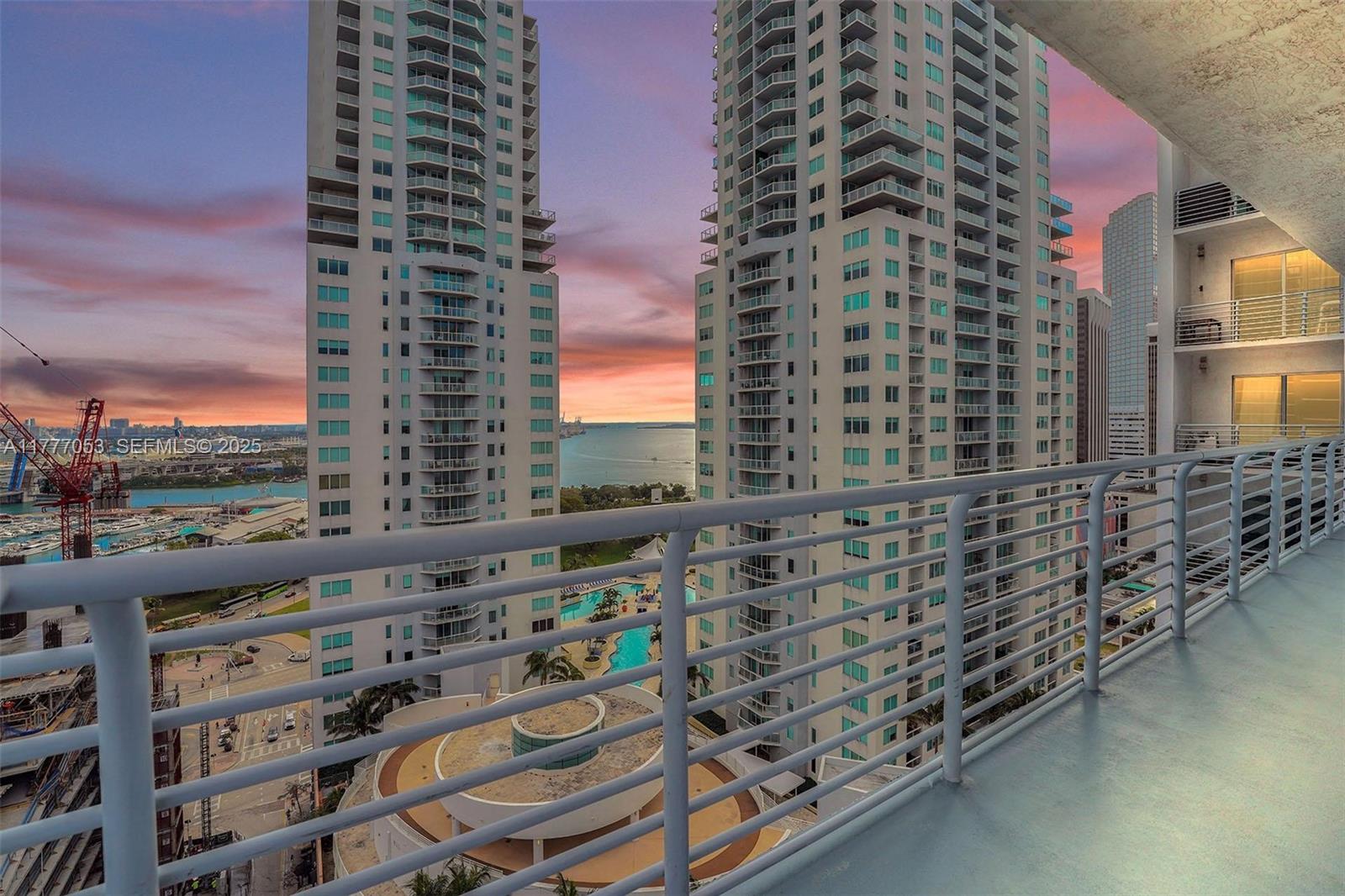 A high-rise balcony overlooks a swimming pool, two residential towers, and a sunset harbor view — 234 NE 3rd St # 2202, Miami FL 33132, MIAMI, FL