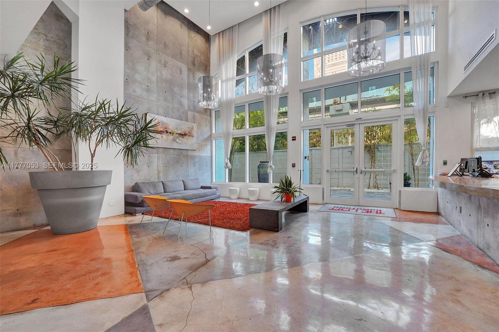 A modern lobby features high ceilings, concrete walls, large windows, and a polished concrete floor — 234 NE 3rd St # 2202, Miami FL 33132, MIAMI, FL