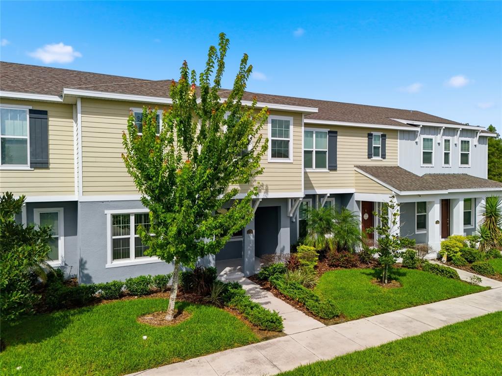 A two-story townhouse with beige and gray siding, a front walkway, and a small tree — 5106 SEA MIST LANE, WESLEY CHAPEL, FL