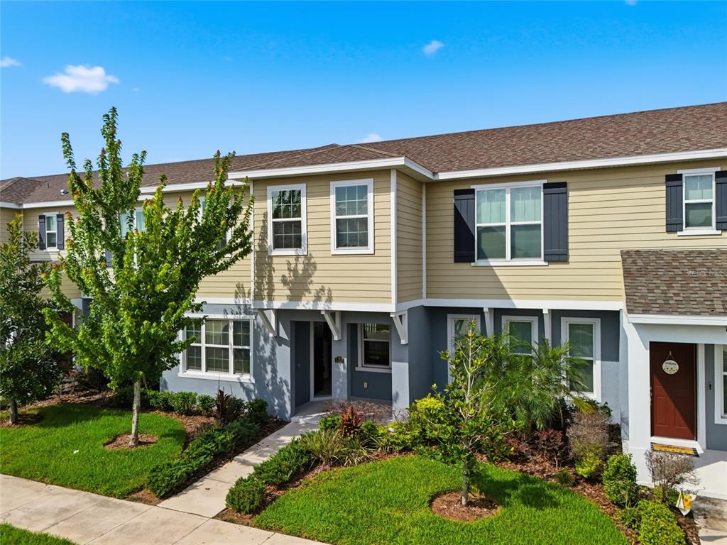 A two-story townhouse with tan siding, gray lower walls, and a small front yard — 5106 SEA MIST LANE, WESLEY CHAPEL, FL