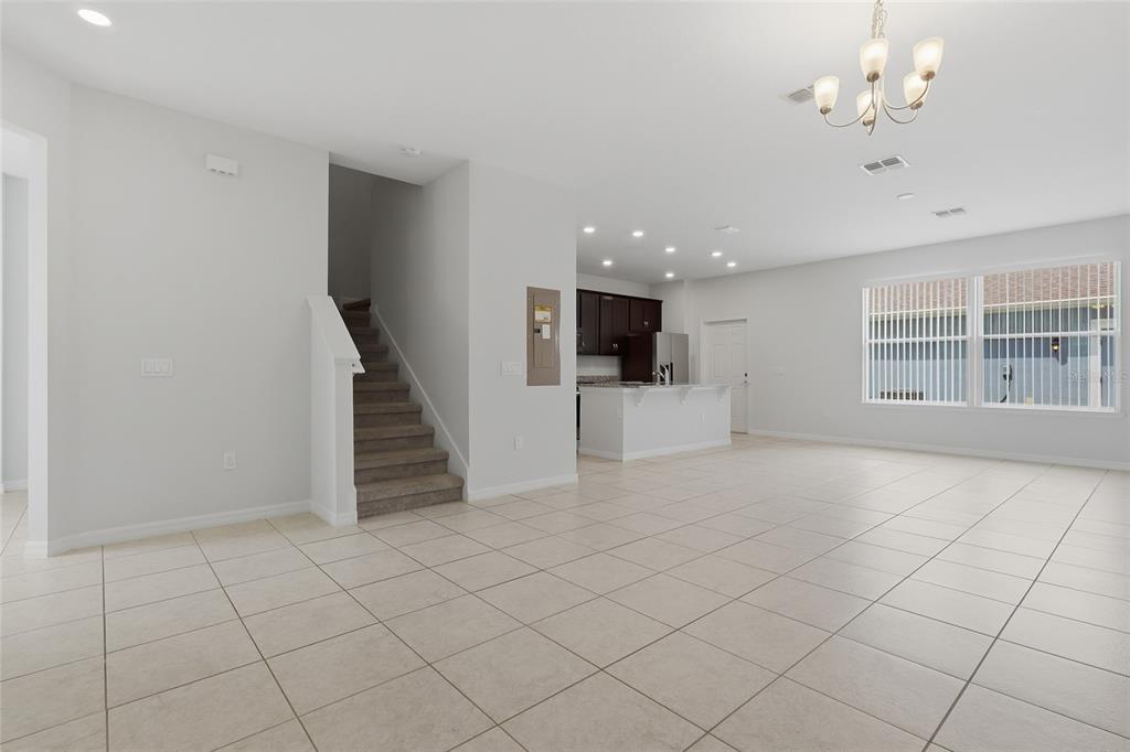 An open-concept living area features light tile flooring, a carpeted staircase, and a kitchen island — 5106 SEA MIST LANE, WESLEY CHAPEL, FL