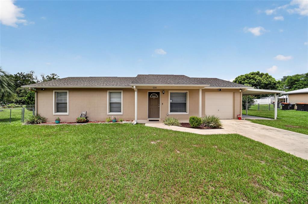 A single-story house with a tan exterior, a front door, a garage, and a carport — 5245 SE 107TH PLACE, BELLEVIEW, FL