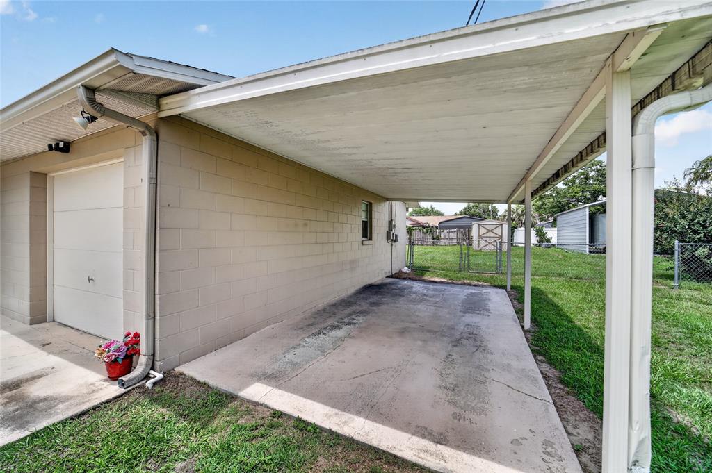 A concrete driveway sits under a covered carport attached to a beige block house — 5245 SE 107TH PLACE, BELLEVIEW, FL