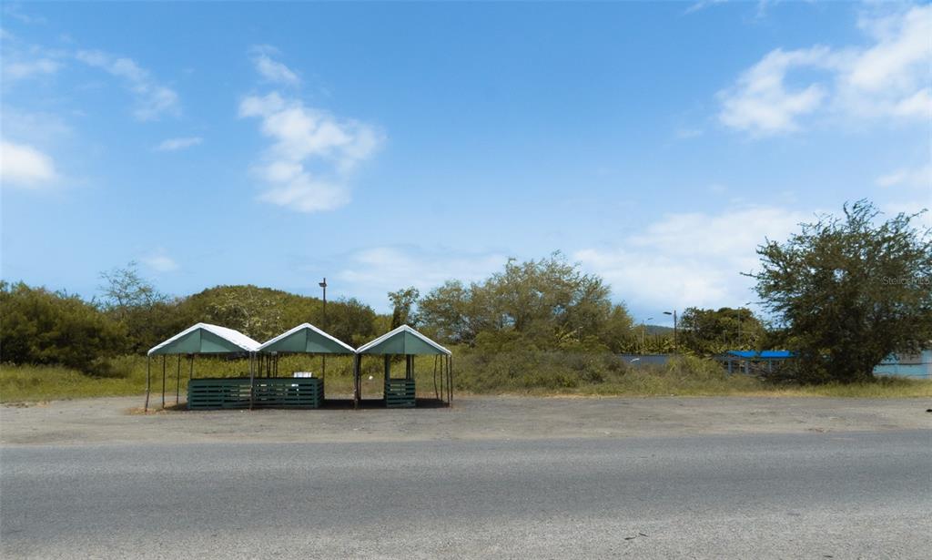 A roadside view of three connected green-roofed stalls on a gravel lot — 971 CAMINO EL DUQUE, NAGUABO, PR