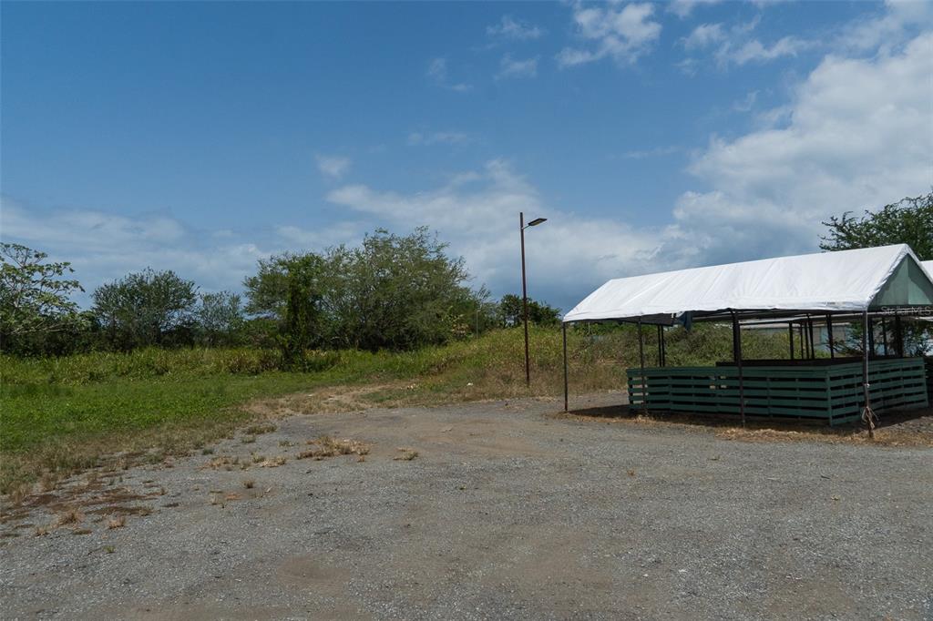 A gravel lot features a green wooden structure with a white canopy under a blue sky — 971 CAMINO EL DUQUE, NAGUABO, PR