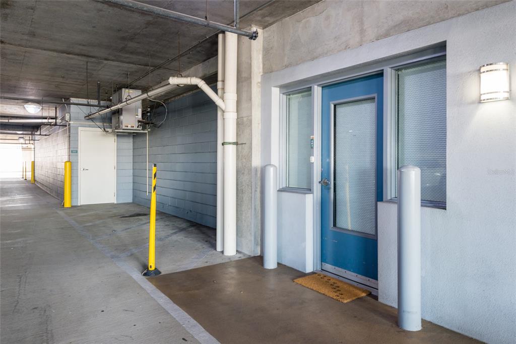 A blue door with a glass panel sits in a concrete parking garage area — 777 N ASHLEY DRIVE UNIT 401, TAMPA, FL