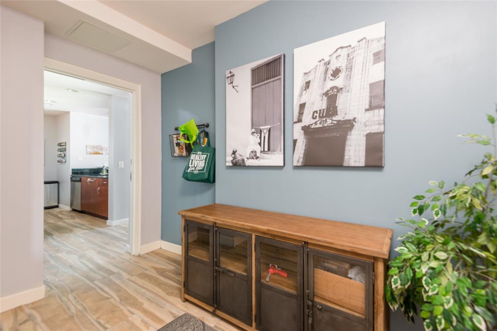 A hallway features a wooden console table, two wall canvases, and a view into a kitchen — 777 N ASHLEY DRIVE UNIT 401, TAMPA, FL