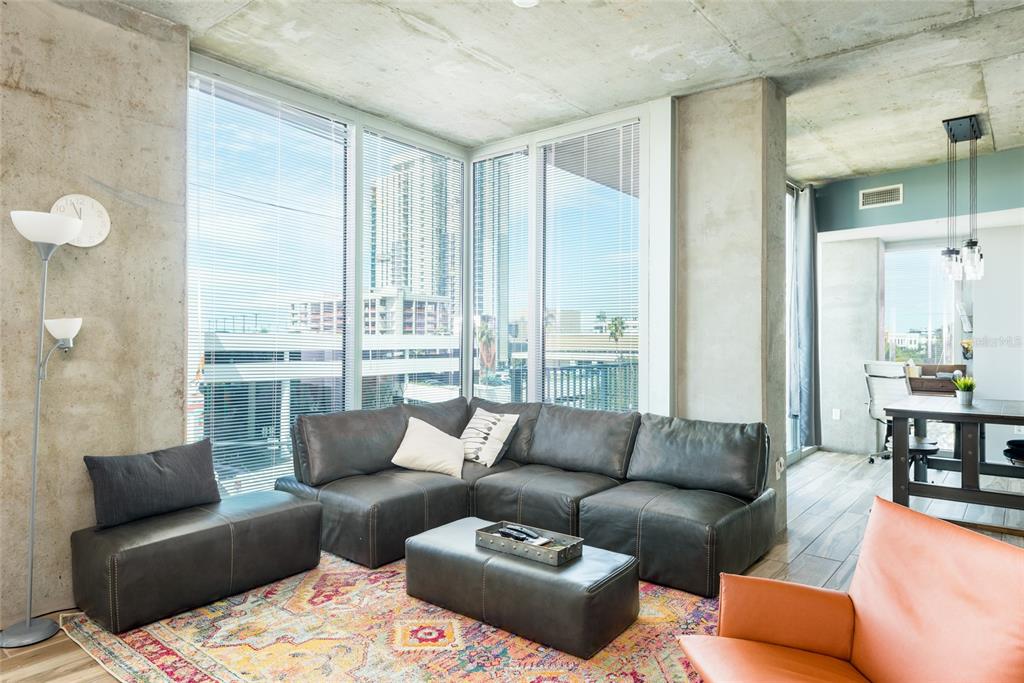 A modern living room features concrete walls, floor-to-ceiling windows, and a sectional sofa — 777 N ASHLEY DRIVE UNIT 401, TAMPA, FL
