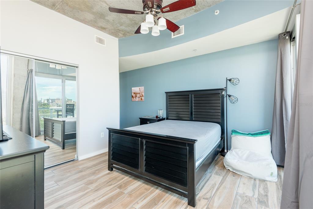 A bedroom features a black bed frame, blue accent wall, ceiling fan, and mirrored closet doors — 777 N ASHLEY DRIVE UNIT 401, TAMPA, FL