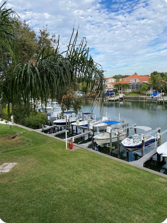 A grassy lawn overlooks a canal with several boats docked at private slips — 1125 PINELLAS BAYWAY S UNIT 201 furnished, ST PETERSBURG, FL