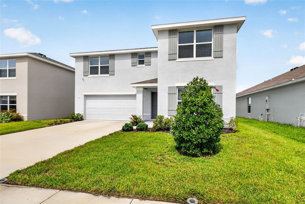 A two-story suburban house with a light gray stucco exterior, a garage, and a lawn — 7622 ROSEWOOD GARDEN LOOP, TAMPA, FL