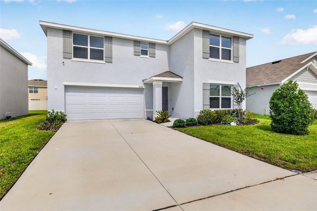 A two-story suburban house with a light gray stucco exterior, a garage, and a driveway — 7622 ROSEWOOD GARDEN LOOP, TAMPA, FL