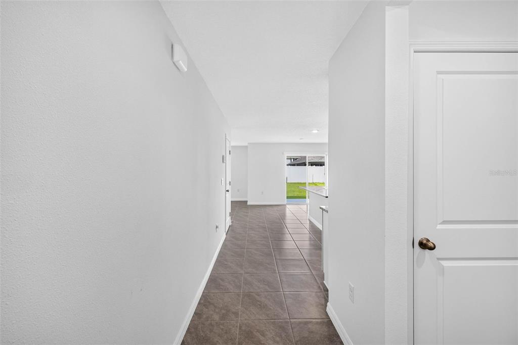 A tiled hallway leads toward an open kitchen and a sliding glass door to the backyard — 7622 ROSEWOOD GARDEN LOOP, TAMPA, FL