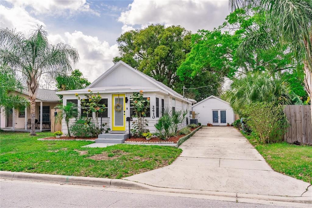A white cottage with a yellow front door and a detached garage sits on a lot — 2410 CENTER AVENUE, ORLANDO, FL