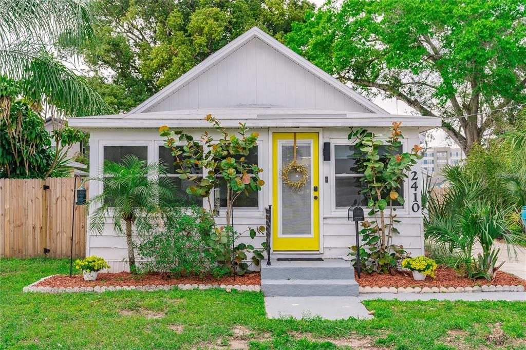 A white cottage with a bright yellow front door and a small front porch — 2410 CENTER AVENUE, ORLANDO, FL