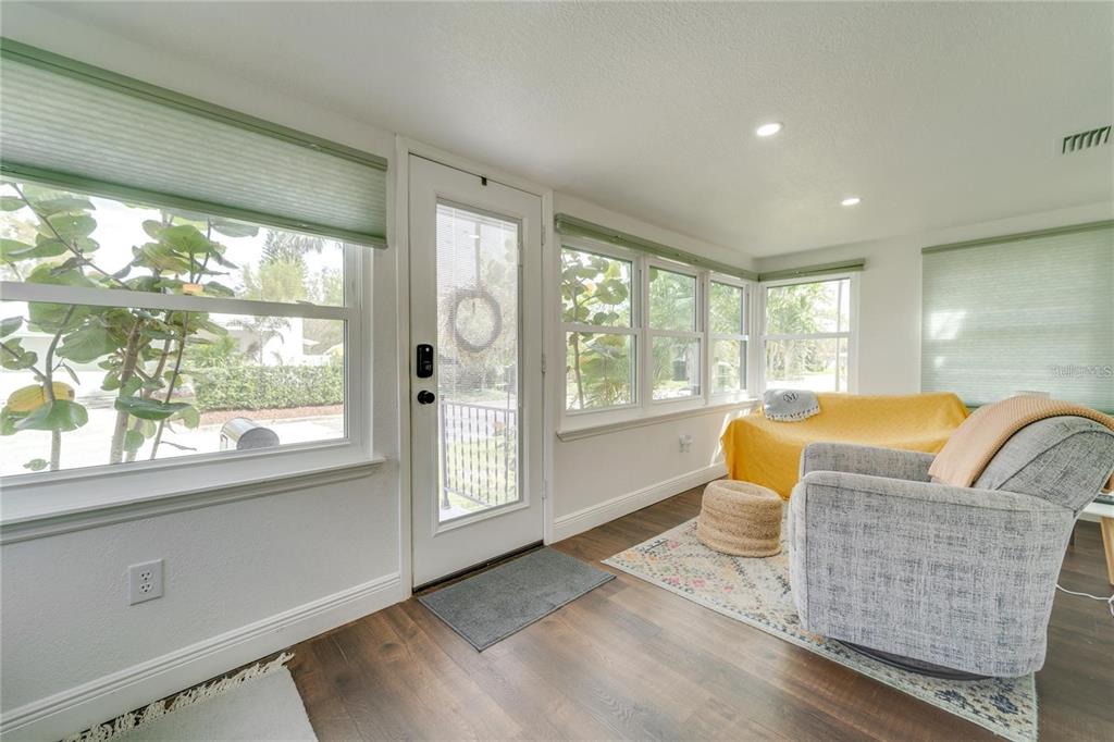 A sunroom with dark wood floors, a glass-paneled door, and large windows with green shades — 2410 CENTER AVENUE, ORLANDO, FL