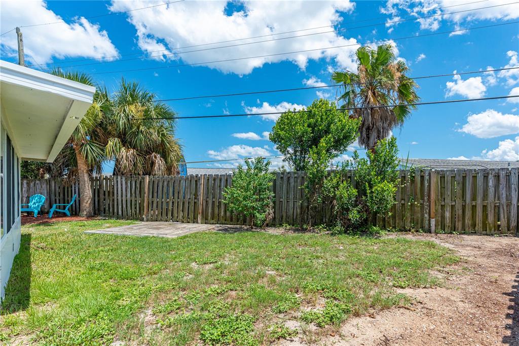 A backyard features a grass lawn, a small concrete pad, and a wooden privacy fence — 28 BEECHWOOD DRIVE, ORMOND BEACH, FL