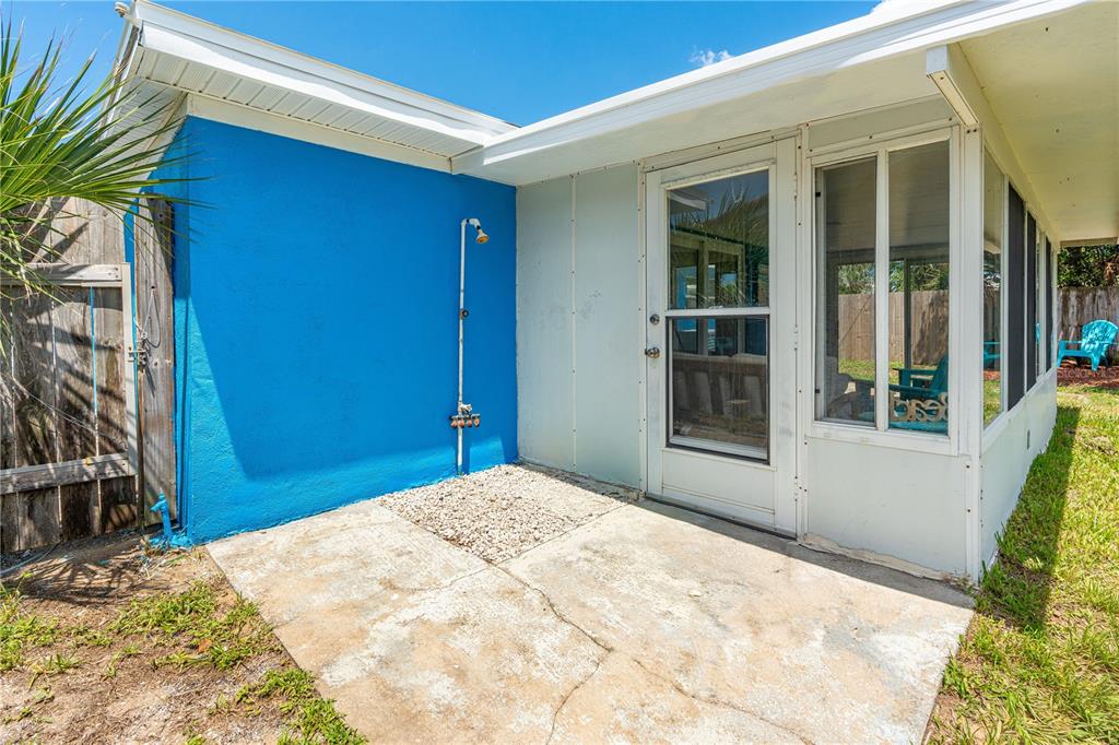 A blue exterior wall with an outdoor shower sits next to a screened-in porch area — 28 BEECHWOOD DRIVE, ORMOND BEACH, FL