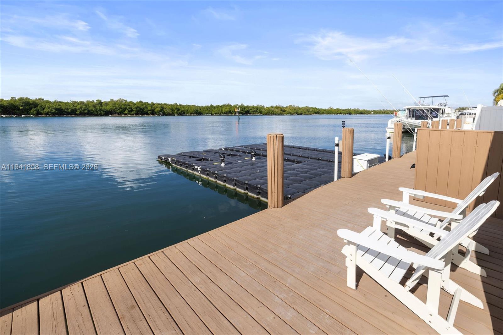 A wooden dock features white Adirondack chairs and a floating platform on calm water — 1908 N Ocean Dr, Hollywood FL 33019, HOLLYWOOD, FL