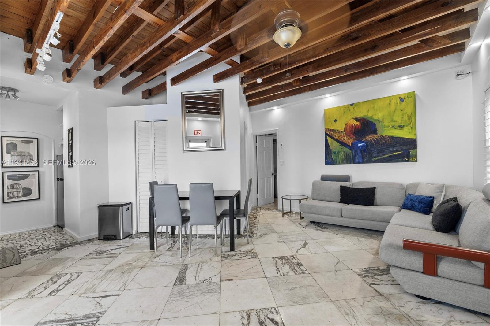 A living and dining area features white marble floors, exposed wood ceiling beams, and furniture — 1908 N Ocean Dr, Hollywood FL 33019, HOLLYWOOD, FL