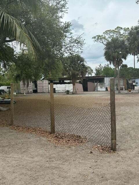 A chain-link fence stands in the foreground of a gravel lot with palm trees — 3525 D Rd Road, FL 33470, FL