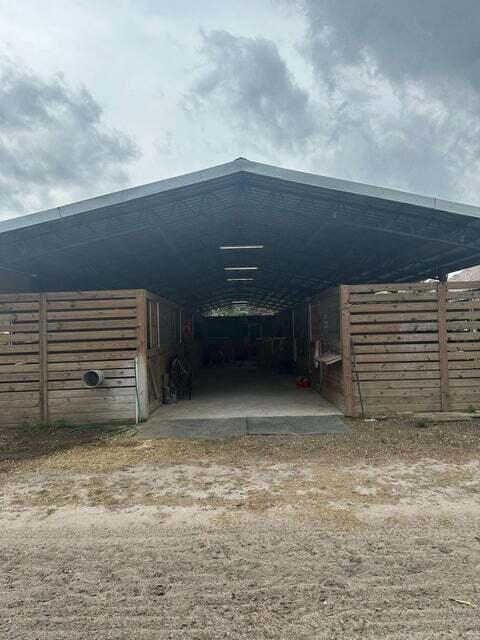 An open-air horse barn with a metal roof and wooden stall partitions — 3525 D Rd Road, FL 33470, FL