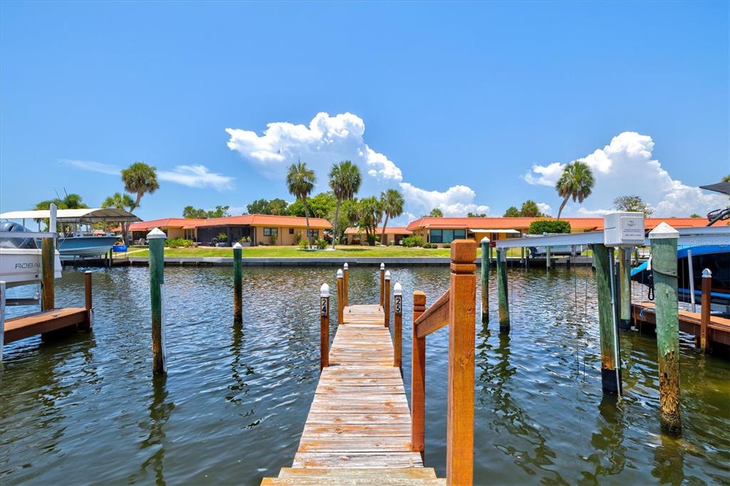 A wooden boat dock extends into a canal toward single-story buildings under a blue sky — 9604 CORTEZ ROAD W UNIT 134, BRADENTON, FL