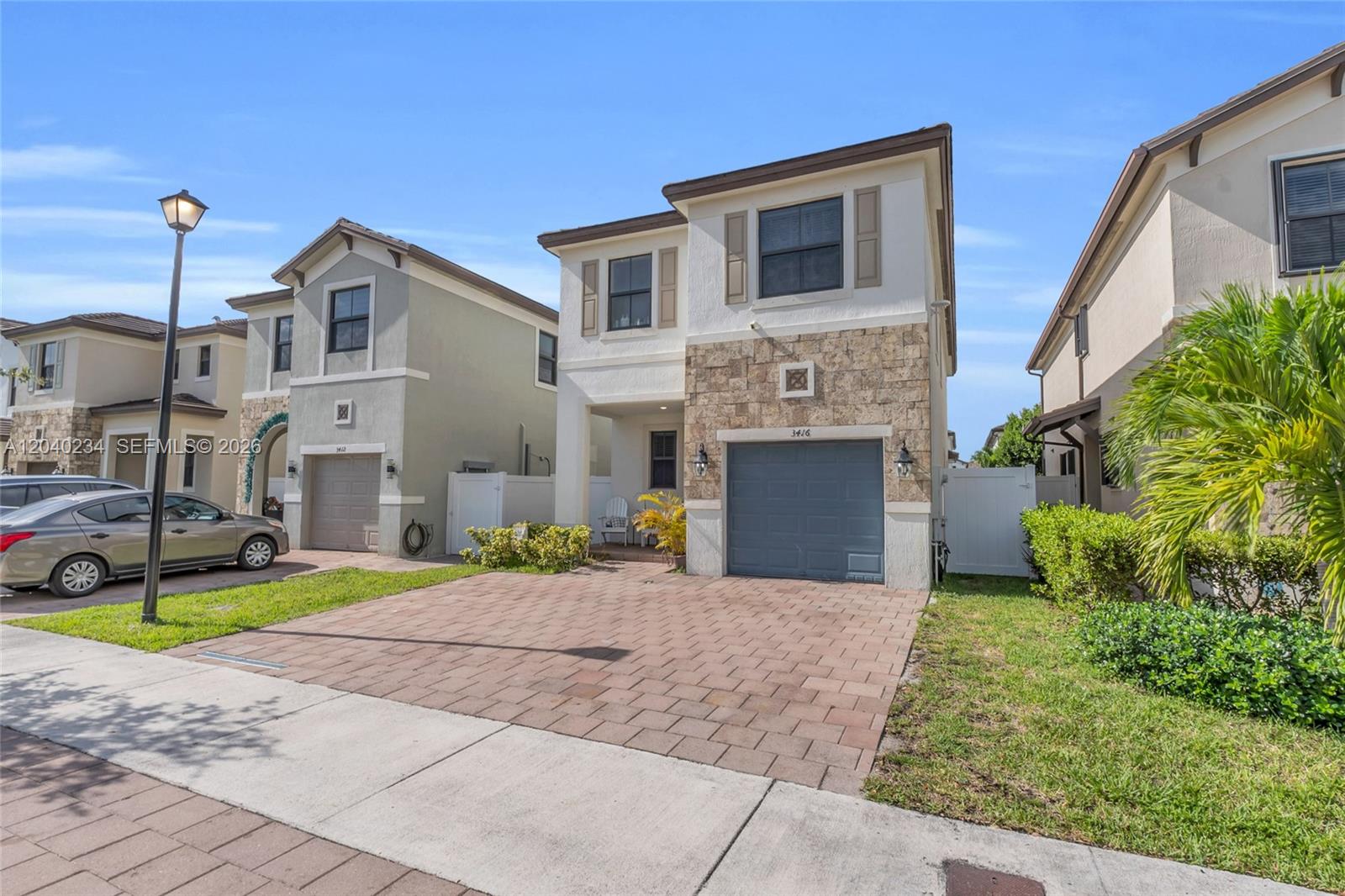 A two-story house with a stone facade, a gray garage door, and a paved driveway — 3416 W 109th Pl, Hialeah FL 33018, HIALEAH, FL