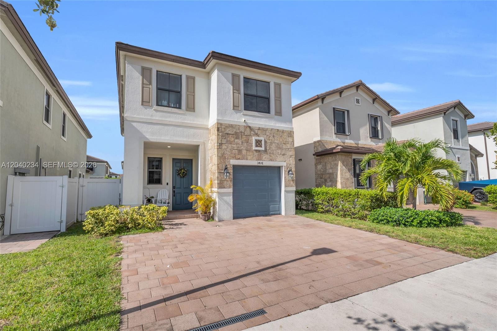 A two-story house features a stone facade, a blue garage door, and a paved driveway — 3416 W 109th Pl, Hialeah FL 33018, HIALEAH, FL