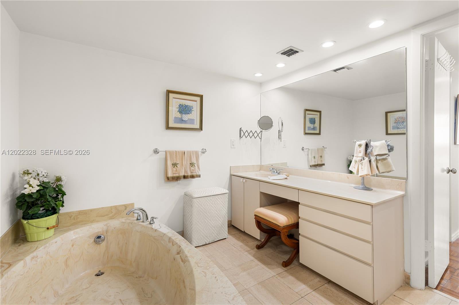A bathroom features a soaking tub, a vanity with a stool, and a large mirror — 210 Sea View Dr # 611, Key Biscayne FL 33149, KEY BISCAYNE, FL