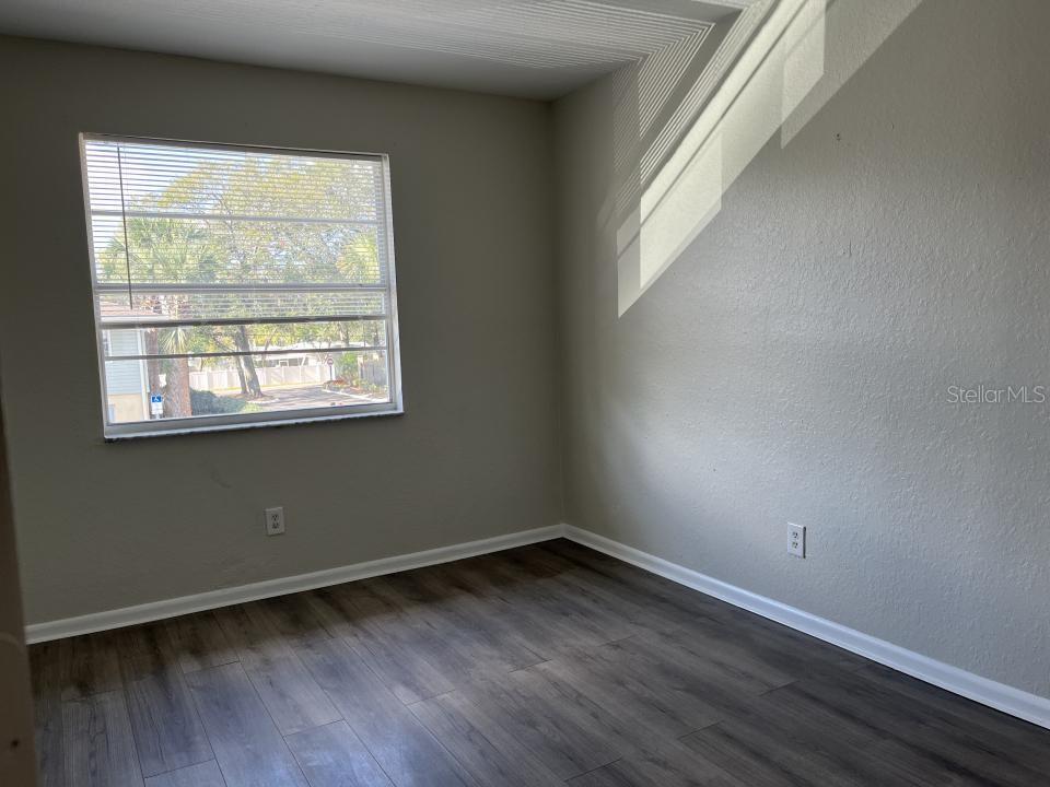 An empty room with gray walls, wood-look flooring, and a single window with blinds — 624 GOLDEN RAINTREE PLACE UNIT 624, BRANDON, FL