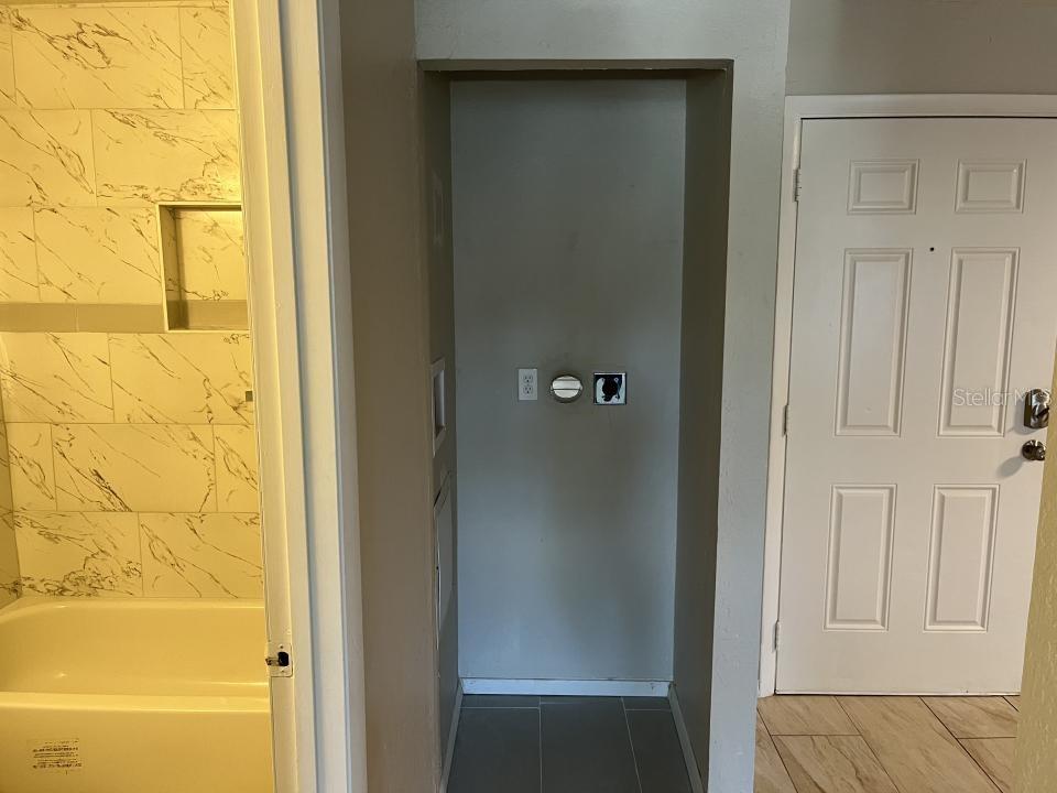 A laundry alcove with utility hookups is situated between a tiled bathroom and a white door — 624 GOLDEN RAINTREE PLACE UNIT 624, BRANDON, FL