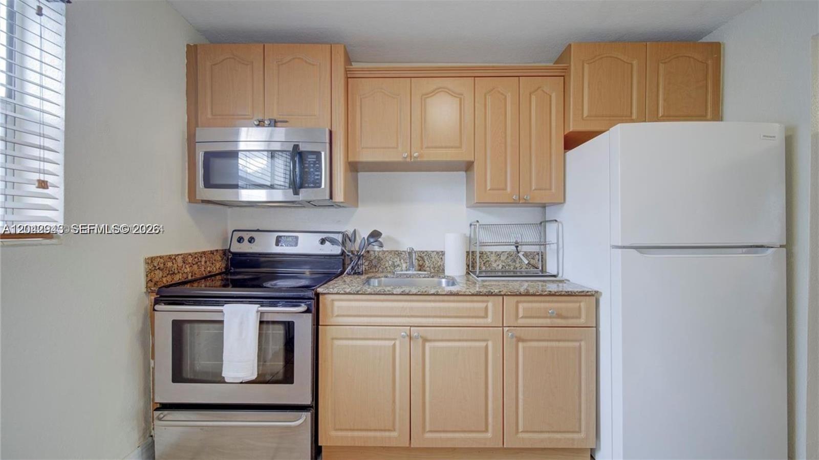 A small kitchen features light wood cabinets, granite countertops, and stainless steel appliances — 427 SW 6th St # 4, Miami FL 33130, MIAMI, FL