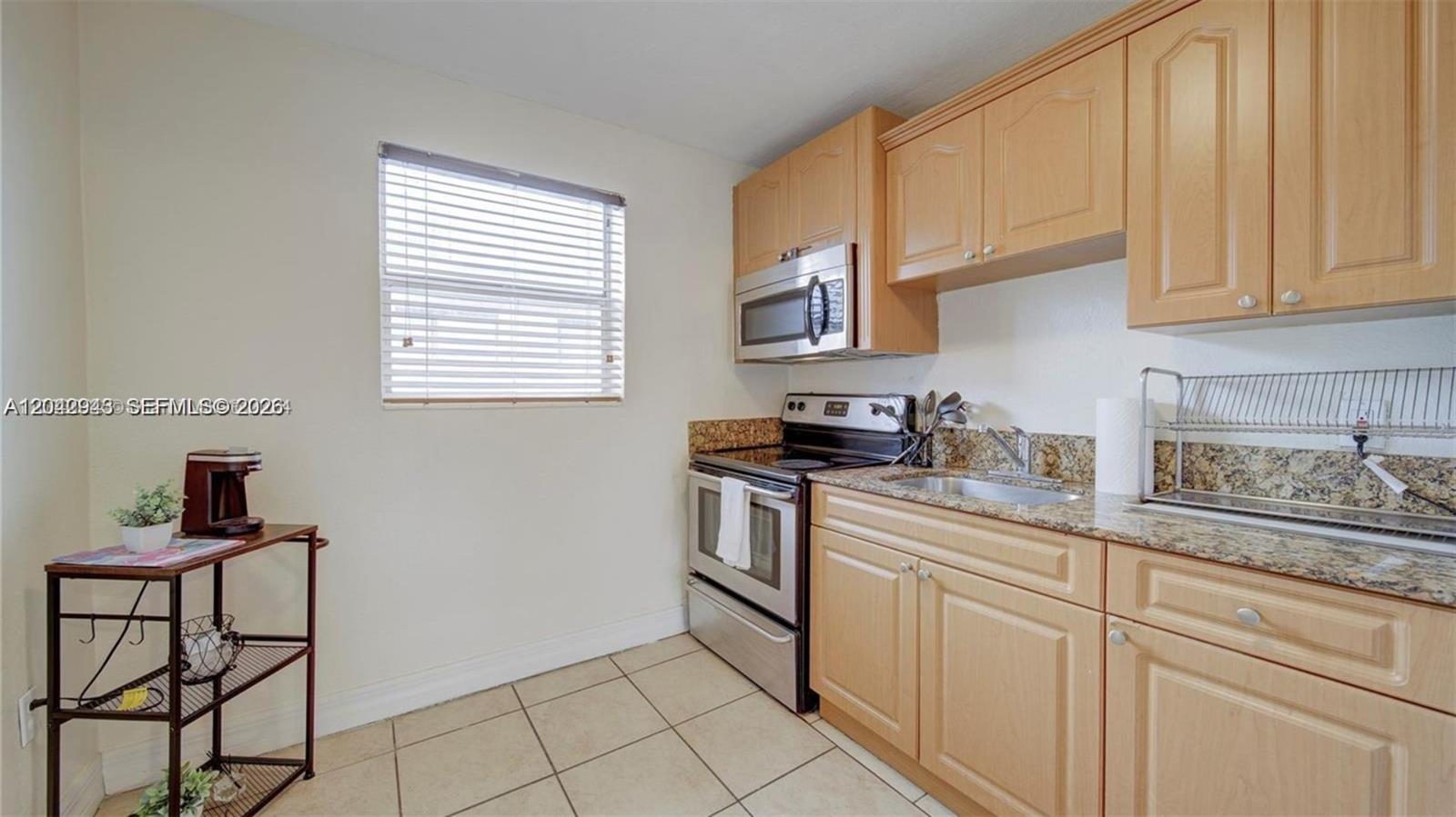 A kitchen features light wood cabinets, granite countertops, stainless steel appliances, and tile flooring — 427 SW 6th St # 4, Miami FL 33130, MIAMI, FL