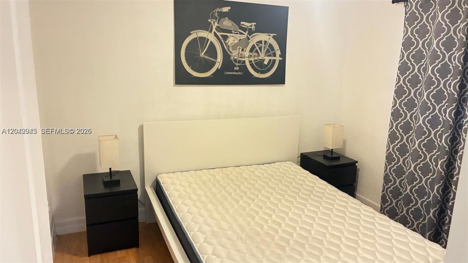 A bedroom features a white bed frame, two black nightstands, and a motorcycle wall print — 427 SW 6th St # 4, Miami FL 33130, MIAMI, FL
