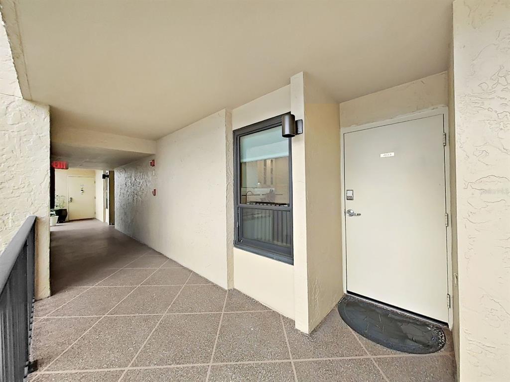 An exterior view of a building hallway featuring a white door and a window — 2620 COVE CAY DRIVE UNIT 403, CLEARWATER, FL
