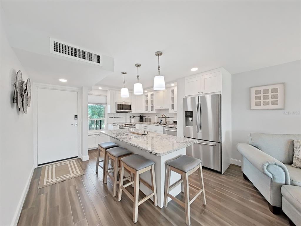 A kitchen with a granite-topped island, stainless steel appliances, and gray wood-look flooring — 2620 COVE CAY DRIVE UNIT 403, CLEARWATER, FL
