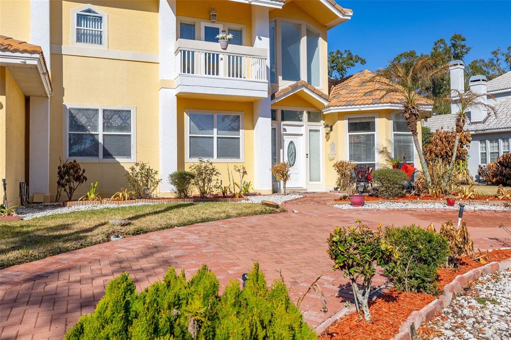 A two-story yellow house with a three-car garage and a paved driveway at sunset — 2747 KISSIMMEE BAY CIRCLE, KISSIMMEE, FL