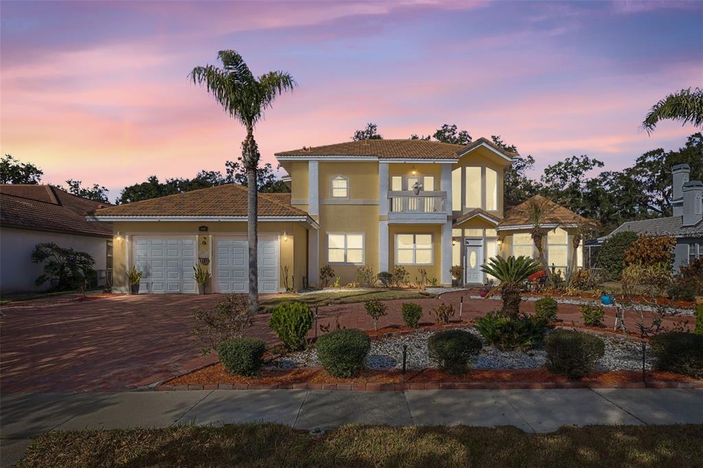 A two-story yellow house features a brick driveway, a balcony, and a front entrance — 2747 KISSIMMEE BAY CIRCLE, KISSIMMEE, FL