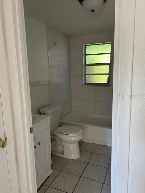 A bathroom features a white vanity, a toilet, and a bathtub with tiled walls — 8129 CASS ROAD, ZEPHYRHILLS, FL
