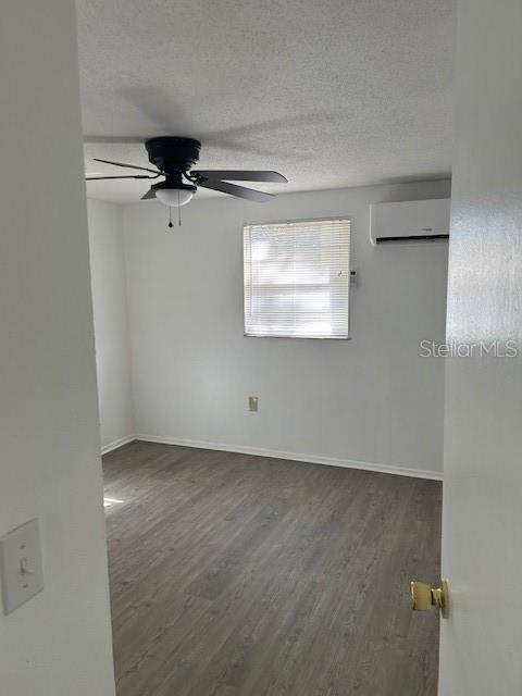 An empty bedroom features light wood-look flooring, a ceiling fan, and a wall-mounted air conditioner — 8129 CASS ROAD, ZEPHYRHILLS, FL