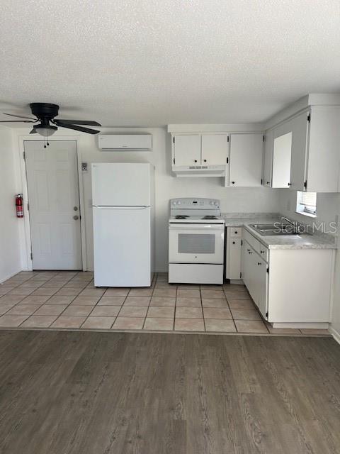 A kitchen features white cabinets, a white refrigerator, a white stove, and tile flooring — 8129 CASS ROAD, ZEPHYRHILLS, FL