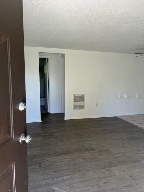 An interior view shows a room with wood-look flooring, white walls, and a hallway entrance — 8129 CASS ROAD, ZEPHYRHILLS, FL
