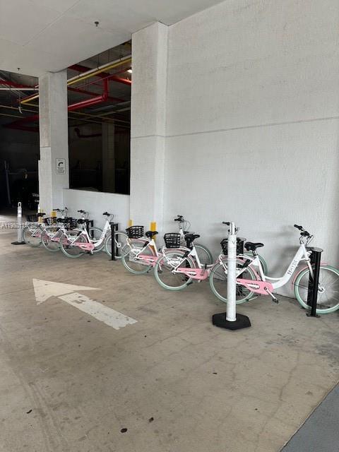 A row of white and pink rental bicycles is parked in a concrete parking garage — 4010 S Ocean Dr # R2702, Hollywood FL 33019, HOLLYWOOD, FL