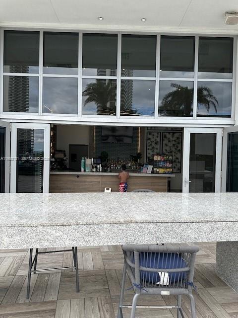 An outdoor bar area features a granite countertop, a high chair, and large glass windows — 4010 S Ocean Dr # R2702, Hollywood FL 33019, HOLLYWOOD, FL