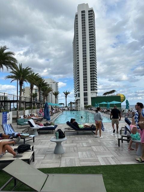 A tall residential skyscraper overlooks a swimming pool area with lounge chairs and palm trees — 4010 S Ocean Dr # R2702, Hollywood FL 33019, HOLLYWOOD, FL